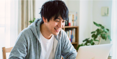 パソコンに向かって微笑みながら学習する男性